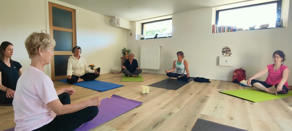 Groupe en méditation assise sur les tapis du studio de Paramé, autour de deux bougies